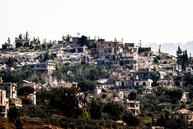  عَلم إسرائيلي مرفوع على مبانٍ مدمرة في بلدة حولا المحتلة جنوب لبنان (أ.ف.ب)