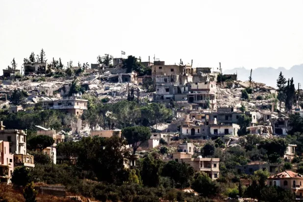 Lübnan'ın güneyinde işgal altındaki Hula kasabasında yıkılmış binaların üzerine İsrail bayrağı asıldı (AFP)
