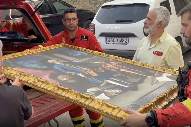 This screen grab of a handout video taken and released by Spain's Military Emergencies Unit (UME) shows firefighters taking away a painting amid a wildfire threatening San Juan de la Pena Monastery in Penas de Riglos in the Spanish southwestern province of Aragon, on August 13, 2026. (Photo by Handout / UME / AFP) 