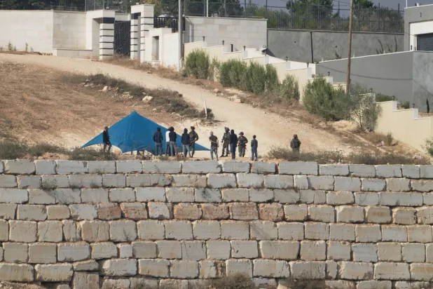 Soldiers evacuate Israeli settlers before dismantling their tent in front of one of the three homes belonging to Palestinian families besieged by settlers for six days in Qusra (AP)