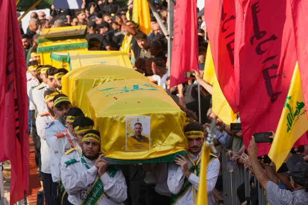 يحمل عناصر من كشافة «حزب الله» نعوش القيادي علي الحاج حسن وزوجته وأطفاله الأربعة الذين قُتلوا السبت في غارة إسرائيلية وذلك خلال موكب تشييعهم بالضاحية الجنوبية يوم الأحد (أ.ب)