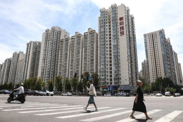 People cross a street past highrise buildings in Beijing, China, 17 August 2026. (EPA)