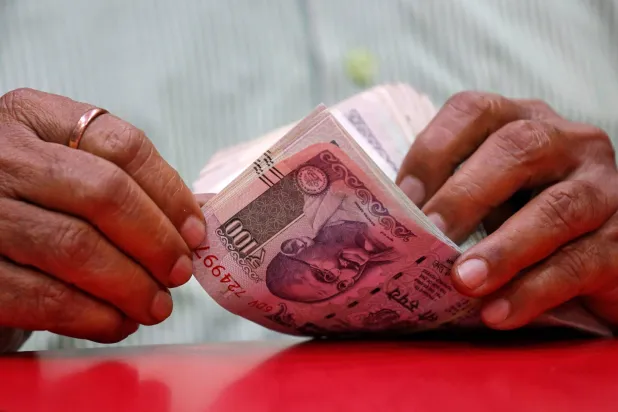 رجل يعدّ أوراقاً نقدية هندية داخل متجر في مومباي (رويترز)