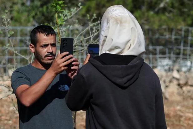 الفلسطيني - الأميركي لؤي أبو ​ريدة يصور مستوطناً داخل أرضه في قرية قصرة بالضفة الغربية المحتلة الثلاثاء (رويترز)