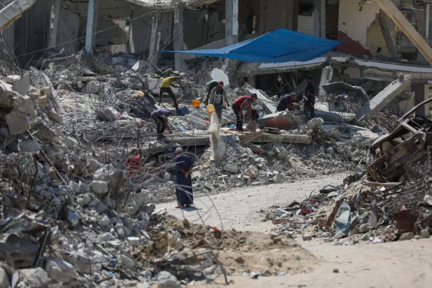 فلسطينيون يستخرجون المعادن من أنقاض المنازل المدمرة في خان يونس لإعادة استخدامها في صنع الخيام بغزة (د.ب.أ)