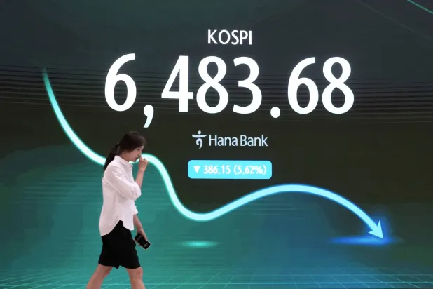 متداول يمر أمام شاشة تعرض مؤشر أسعار الأسهم الكوري المركب في غرفة تداول العملات الأجنبية بمقر بنك هانا (أ.ب)