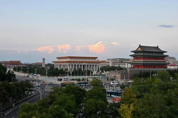 Commuters ride past the Tiananmen Square in Beijing on August 18, 2026. (Photo by ADEK BERRY / AFP)