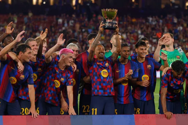 لاعبو برشلونة يحتفلون بالتتويج بكأس خوان غامبر عقب الفوز على الأهلي المصري في ملعب «كامب نو» (أ.ب)

