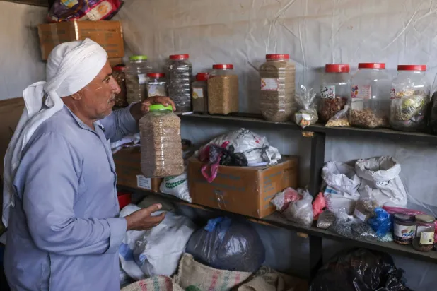 Salem Muhanna, who manages the Al Qarara Seed Bank with support from the International Committee of the Red Cross (ICRC), prepares to stack a container with seeds at the bank, in Deir el-Balah, central Gaza Strip on August 11, 2026. (Photo by Bashar Taleb / AFP)
