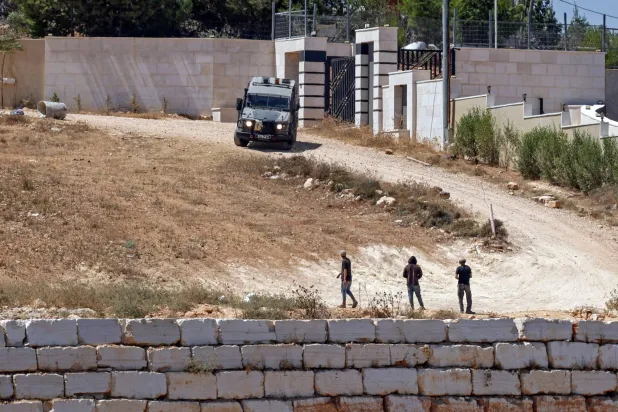 An Israeli military vehicle patrols near to the settlers in front of the Palestinian houses in the village of Qusra, south of Nablus, in the occupied West Bank, on August 13, 2026. (Photo by Zain JAAFAR / AFP)