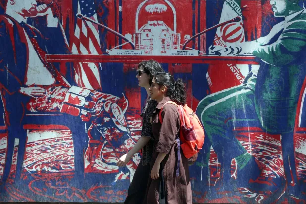إيرانيتان تمران أمام جدارية مناهضة لأميركا قرب السفارة الأميركية السابقة في طهران الاثنين (إ.ب.أ)