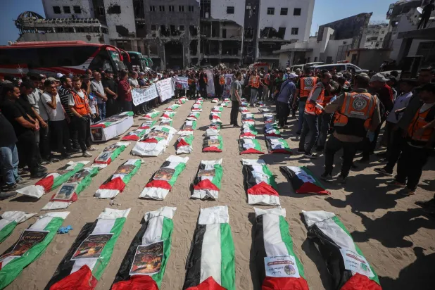 مشيعون يلتفون حول بقايا فلسطينيين قتلوا في ضربات خلال حرب غزة قبيل دفنهم بمدينة غزة يوم الخميس (أ.ف.ب)
