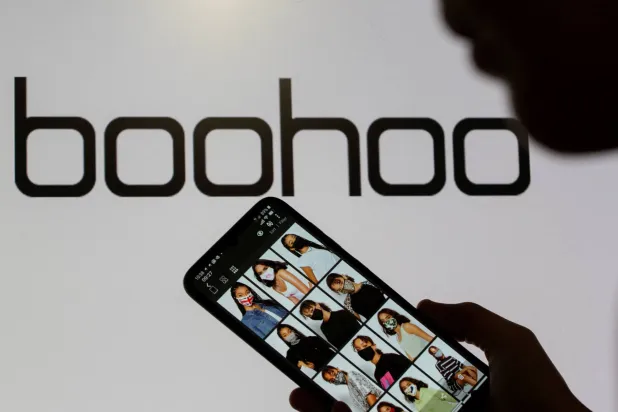FILE PHOTO: A woman poses with a smartphone showing the Boohoo app in front of the Boohoo logo on display in this illustration taken September 30, 2020. REUTERS/Dado Ruvic/Illustration/File Photo
