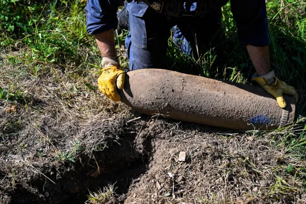 A member of Metz' mine-clearing center, Civil Protection Mine Clearance Task Force (Groupement d’Intervention du Déminage / GID) recovers a WWI German 22cm shell reported by the ONF (Office National des Forêts) in the area of Douaumont, northeastern France on July 8, 2026. (AFP) 