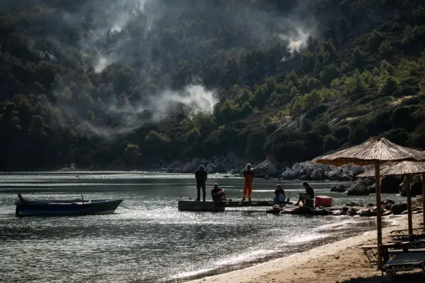Orman yangınının sürdüğü Yunanistan’ın Skiros Adası’ndaki sahildeki insanlar (AFP)