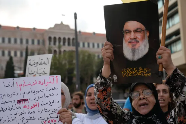 سيدة ترفع صورة أمين عام «حزب الله» السابق حسن نصر الله خلال احتجاج نظّمه الحزب رفضاً للمفاوضات اللبنانية مع إسرائيل (أ.ب)