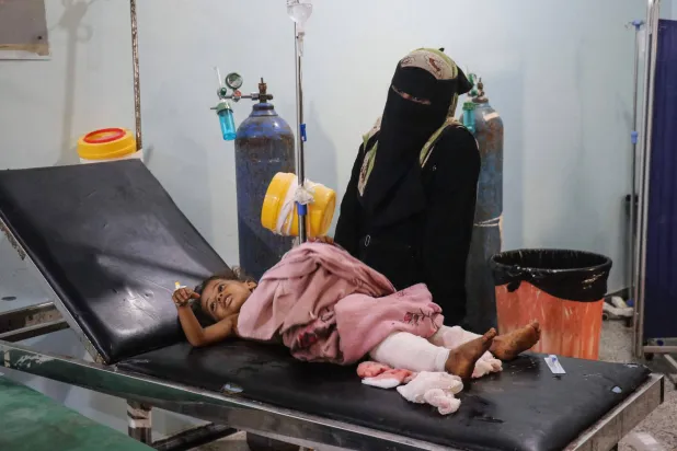 أم يمنية في مستشفى رفقة طفلتها المصابة جراء هجوم حوثي (أ.ف.ب)