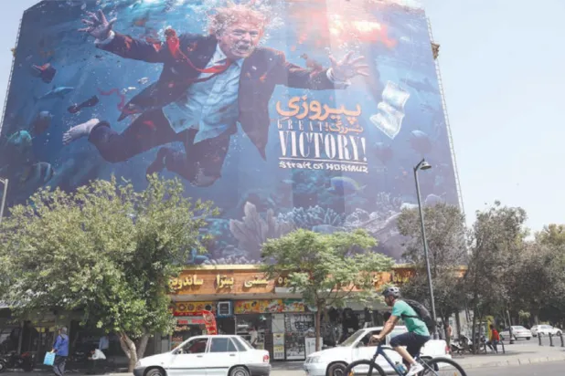 Motorcyclists pass a billboard depicting US President Donald Trump underwater amid explosions, with the words “Great Victory! Strait of Hormuz,” in Tehran, Iran (EPA)