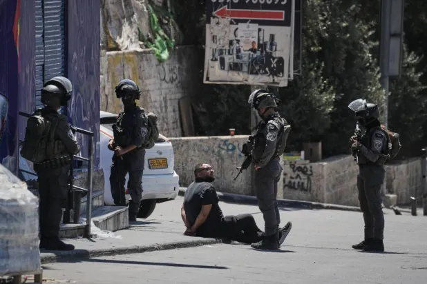رجل فلسطيني مكبل اليدين يُحتجز من قبل ضباط شرطة الحدود الإسرائيلية خلال عملية للجيش في مخيم قلنديا للاجئين في الضفة الغربية (أ.ب)