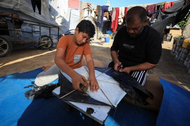Palestinians make a kite at a tent camp sheltering displaced people in Gaza City, August 25, 2026. (Reuters) 