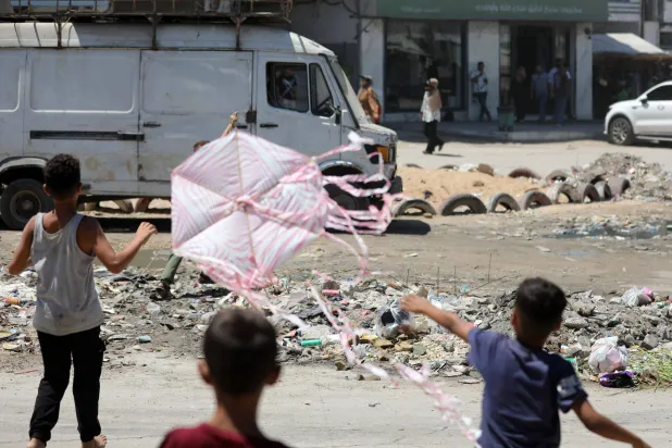 أطفال فلسطينيون يصنعون الطائرات الورقية ويطلقونها في غزة (د.ب.أ)