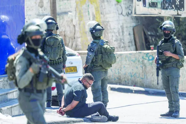 قوات إسرائيلية تعتقل فلسطينياً خلال مداهمة مركز تابع لـ«الأونروا» جنوب رام الله بالضفة الغربية أمس (أ.ف.ب)