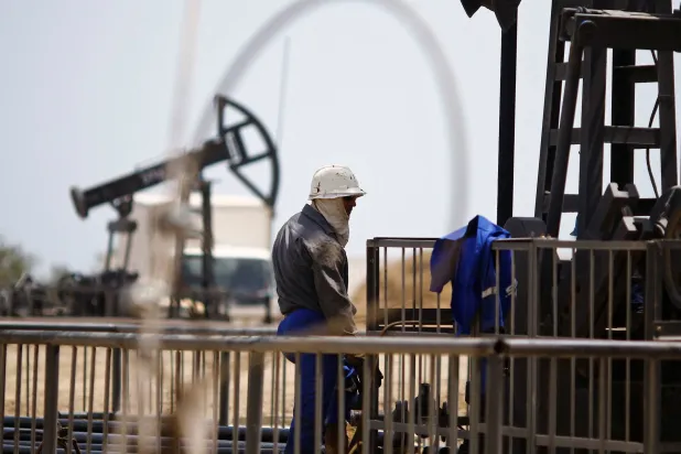 A worker rests next to an oil pump on a sunny day in Baku, Azerbaijan, June 16 , 2015. (Reuters)