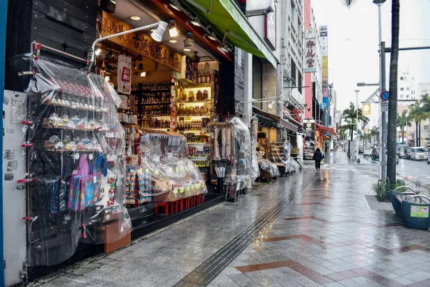 Shops cover their merchandise in plastic to protect it from the rain as Typhoon Saudel passes in Naha on August 26, 2026. (AFP)
