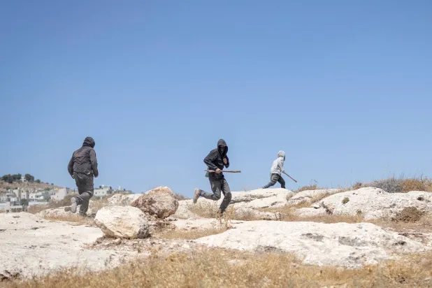 Israeli settlers, holding sticks, arrive to confront left-wing activists at an Israeli outpost in the Israeli-occupied Palestinian village of Jannatah, south of Bethlehem, on August 25, 2026. (AFP)