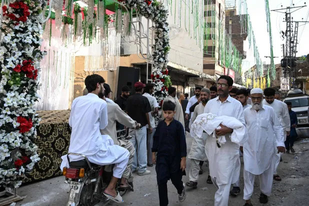 رجل يحمل جثمان طفل حديث الولادة توفي إثر حريق اندلع في جناح صحة الأم والطفل بمستشفى معهد باكستان للعلوم الطبية (أ.ف.ب)
