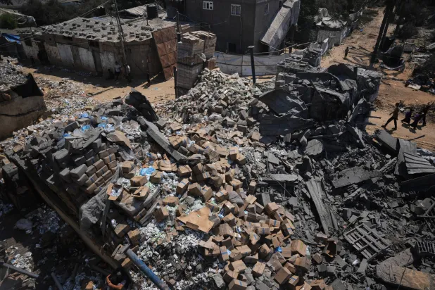  Palestinians walk past a food-aid warehouse damaged in an Israeli airstrike that targeted a nearby house in Deir al-Balah, central Gaza Strip, Wednesday, Aug. 26, 2026. (AP)