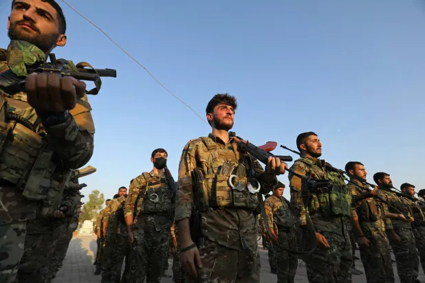 Kurdish fighters from the Qamishli Brigade, part of the Syrian Democratic Forces (SDF) participate in a military parade in Qamishli on August 21, 2026, during the funeral ceremony for three Kurdish fighters killed in previous battles in Aleppo's Sheikh Maqsoud neighborhood in the north of Syria. (AFP)