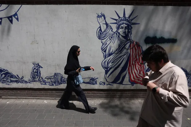 إيرانيون يمرون قرب جدارية مناهضة للولايات المتحدة في طهران - 15 يوليو 2026 (رويترز)