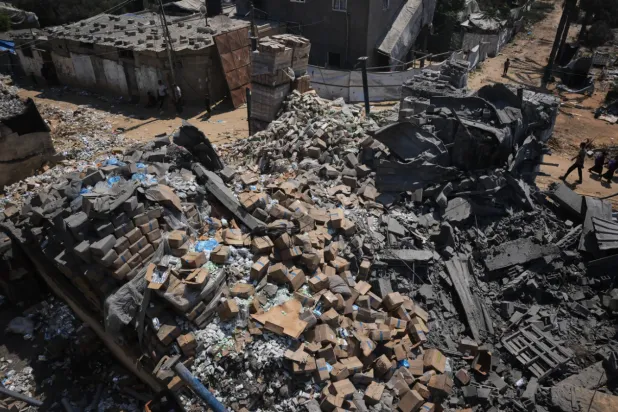 Palestinians walk past a food-aid warehouse damaged in an Israeli airstrike that targeted a nearby house in Deir al-Balah, central Gaza Strip, Wednesday, Aug. 26, 2026. (AP Photo/Abdel Kareem Hana)