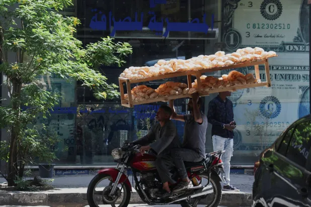 عامل يحمل أرغفة من الخبز وسط العاصمة القاهرة (رويترز)