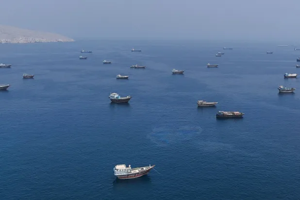 
صورة ملتقطة من شاطئ محافظة مسندم بسلطنة عمان لسفن وزوارق راسية قرب مضيق هرمز أمس (رويترز)