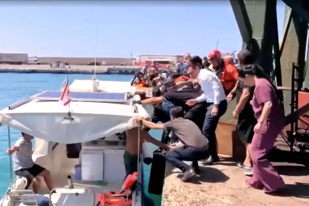 قوارب الإنقاذ تنقل الركاب إلى الشاطئ من قارب انقلب بشمال قبرص في لقطة مأخوذة من مقطع فيديو (رويترز)