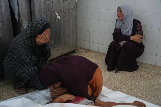 فلسطينيات يبكين على جثمان أحد أقاربهم خلال جنازته في مستشفى الأقصى بدير البلح وسط قطاع غزة (أ.ب)