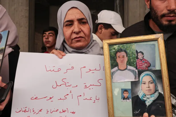 سوريّة تحمل صور أقارب لها قُتلوا في «مجزرة التضامن» بالحي جنوب دمشق 24 أبريل الماضي (إ.ب.أ)