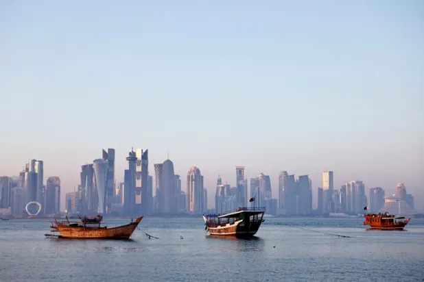 قوارب تُبحر في كورنيش الدوحة بينما يظهر أفق المدينة بالخلفية (رويترز)