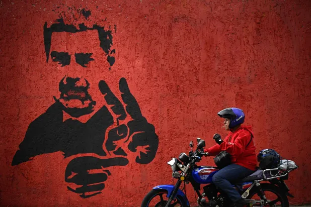 (FILES) A motorcyclist rides past a mural of ousted Venezuela's President Nicolas Maduro flashing the V sign, in Caracas, on May 14, 2026. (Photo by Federico PARRA / AFP)
