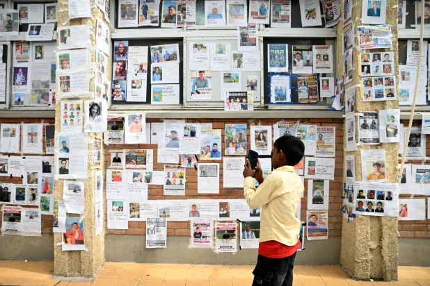 A boy uses a mobile phone to take photos of missing and deceased people pasted on wall outside Tribhuvan University Teaching Hospital, following flash floods and a mudslide, in Kathmandu, Nepal, September 1, 2026. (Reuters)