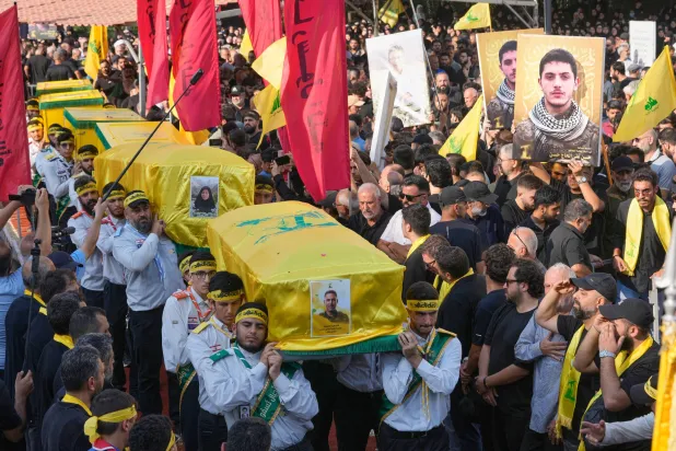 عناصر من كشافة «المهدي» يحملون نعوش قياديّ بـ«حزب الله» وعائلته خلال تشييعهم بالضاحية الجنوبية لبيروت (أ.ب)
