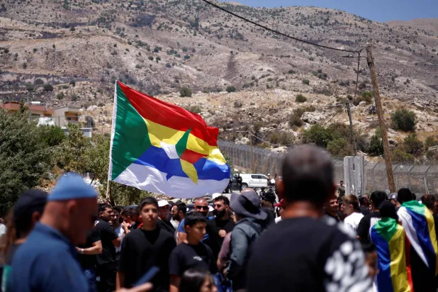 Druze wait near the border fence in the Israeli-annexed Golan Heights village of Majdal Shams, as Syrian Druze who had crossed over the day before, cross back to return to Syrian, on July 17, 2025. (Photo by Jalaa MAREY / AFP)