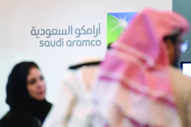 __AFP_Saudi and Foreign investors stand in front of the logo of Saudi state oil giant Aramco during the 10th Global Competitiveness Forum