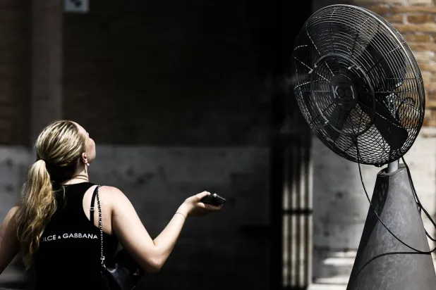 A person cools off in front of a fan as tourists seek relief from high summer temperatures in the Colosseum in Rome, Italy, 28 August 2026. (EPA)