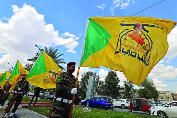 Members of Iraq’s Kataib Hezbollah carry the group’s flag in central Baghdad. (File photo - AFP)