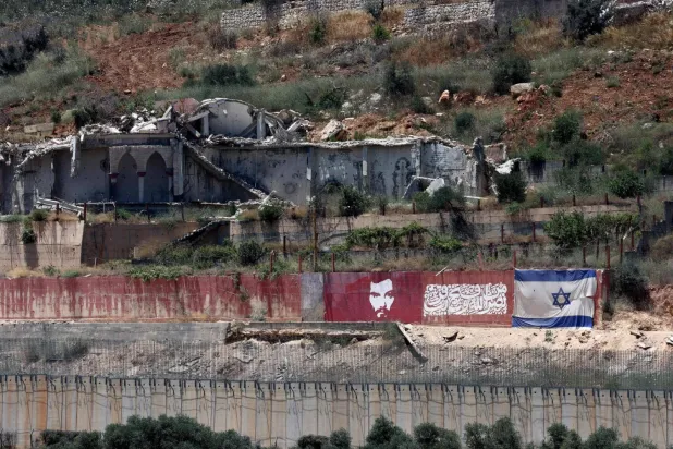 Lübnan sınırındaki bir köyde yıkılmış binanın yanındaki duvara çizilmiş İsrail bayrağı (AFP)