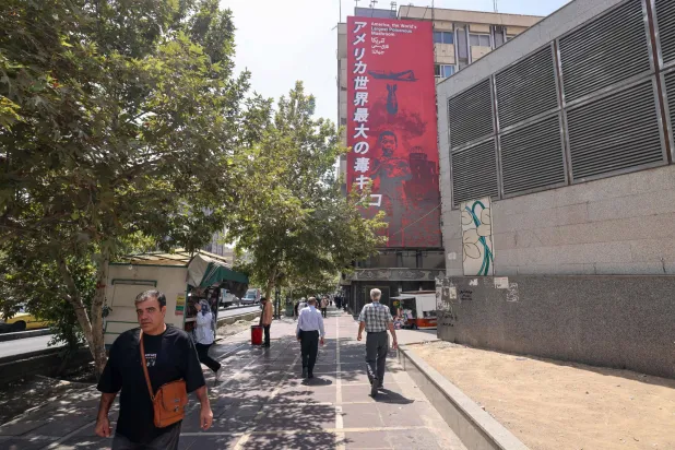 People walk past a large anti-US banner with reference to the dropping of the atomic bomb on the Japanese city of Hiroshima, in Tehran on September 2, 2026. (Photo by Atta KENARE / AFP) / 