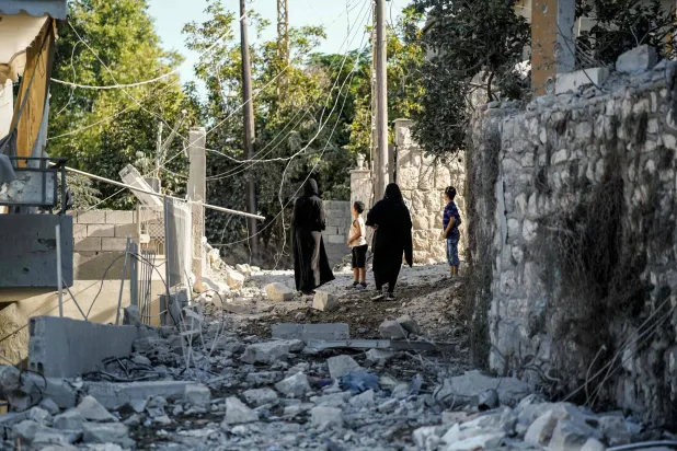 سكان يتفقدون الدمار في صباح اليوم التالي لغارة جوية ليلية شنها الجيش الإسرائيلي واستهدفت قرية ميفدون بجنوب لبنان (أ.ف.ب)